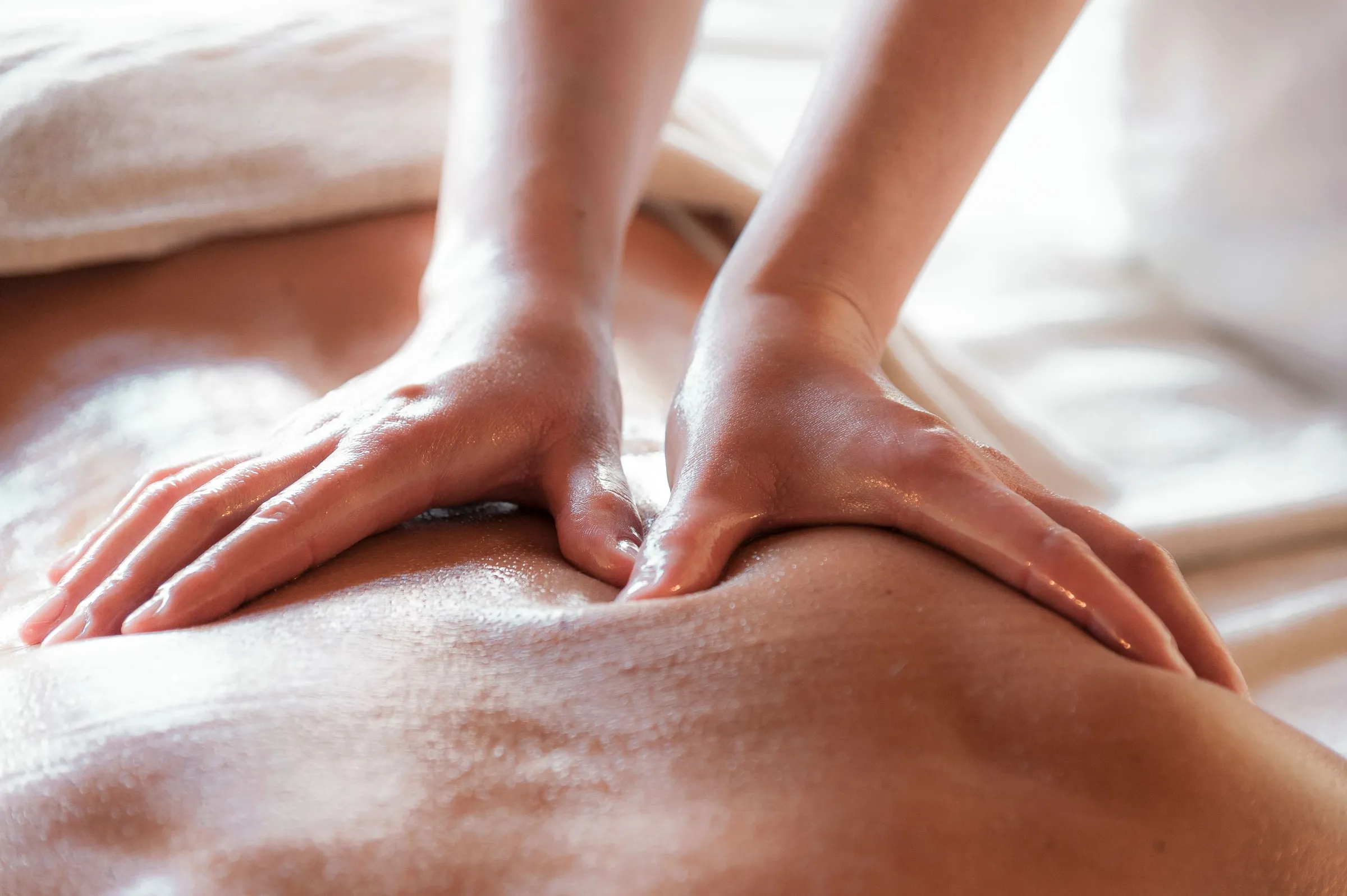 Manos de una kinesióloga aplicando terapia manual sobre la espalda de un paciente como parte de un tratamiento kinesiológico